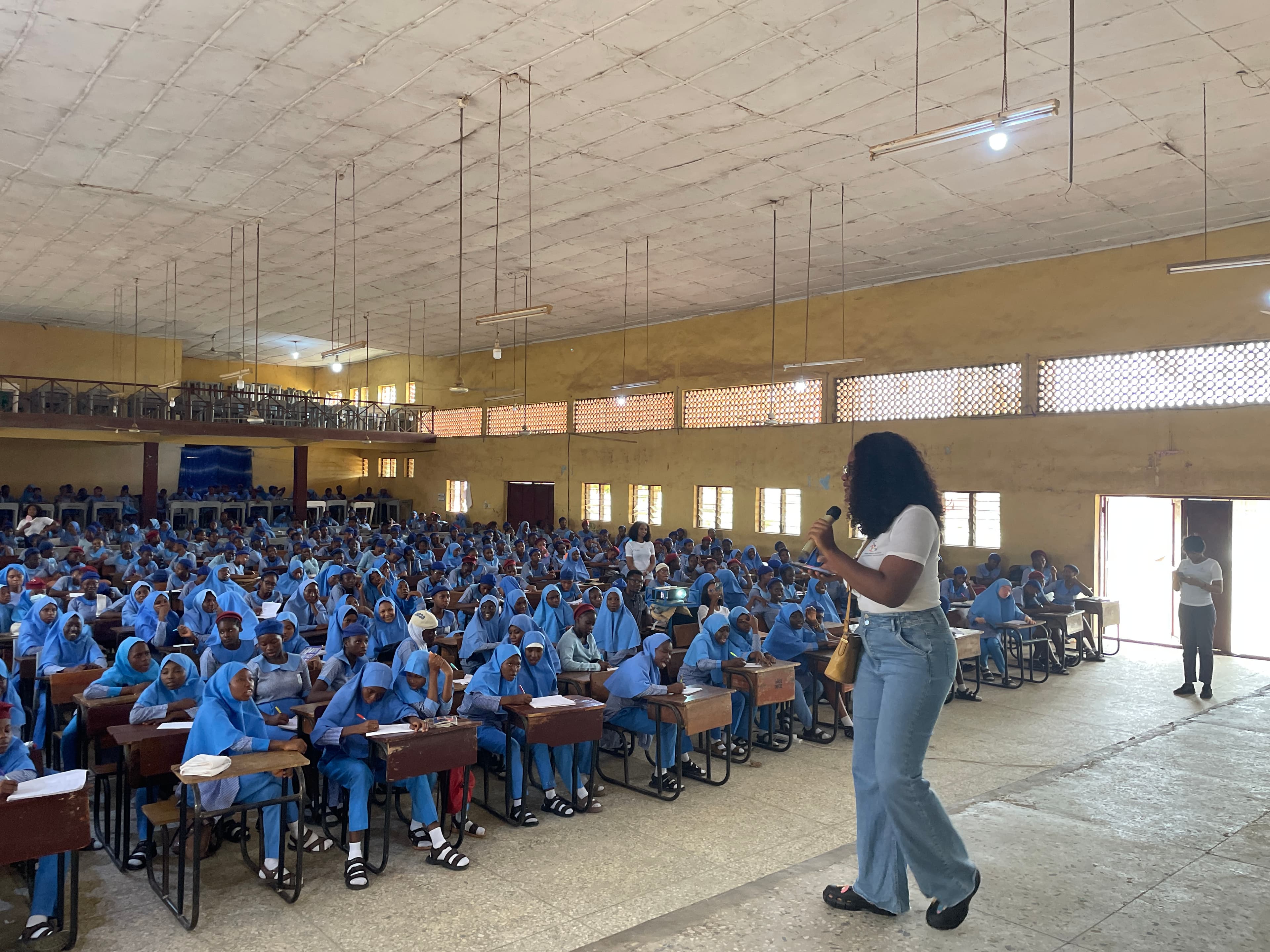 Students in blue uniforms attend an assembly as a speaker addresses them
